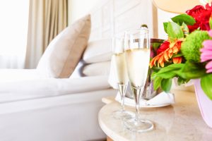 Two filled champagne glasses on a bedside table